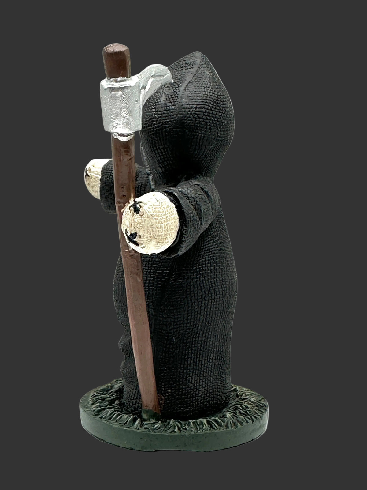 A small collectible Pinhead Monster figurine of a hooded grim reaper or skeleton-like character wearing a black robe and holding a brown staff, standing on a round dark base against a plain black studio background.