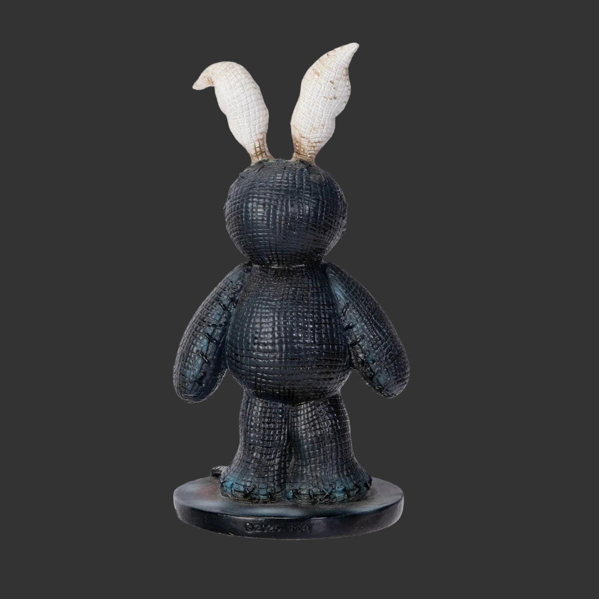 A textured Pinhead Monster Darko black rabbit figurine shown from the back, featuring upright ears made from cold cast resin standing on a round black base against a plain black background.
