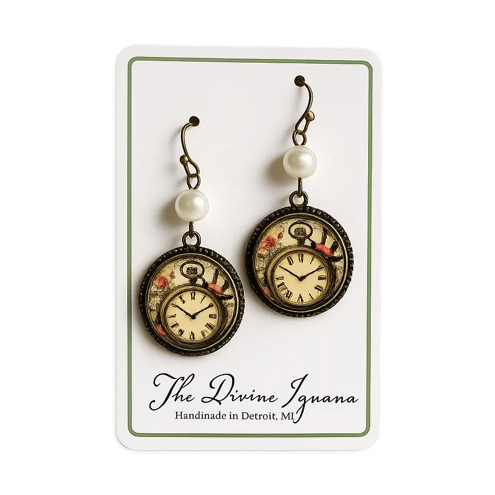 A pair of Alice in Wonderland steampunk-style drop earrings displayed on a white card. Each earring has an antique bronze hook, a white pearl bead, and a round pocket-watch pendant with a floral design and Roman numerals.