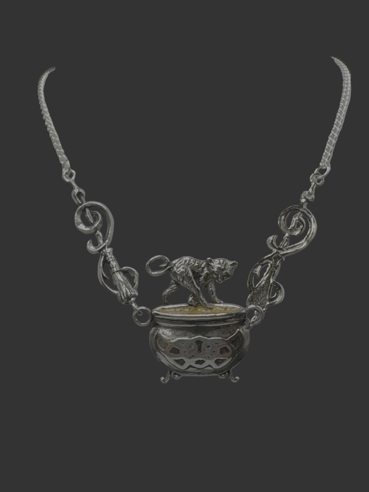 A silver-toned necklace displayed on a white mannequin bust, featuring a central pendant with a small dog figure standing on a bowl-like form and ornate scrollwork details along the chain.