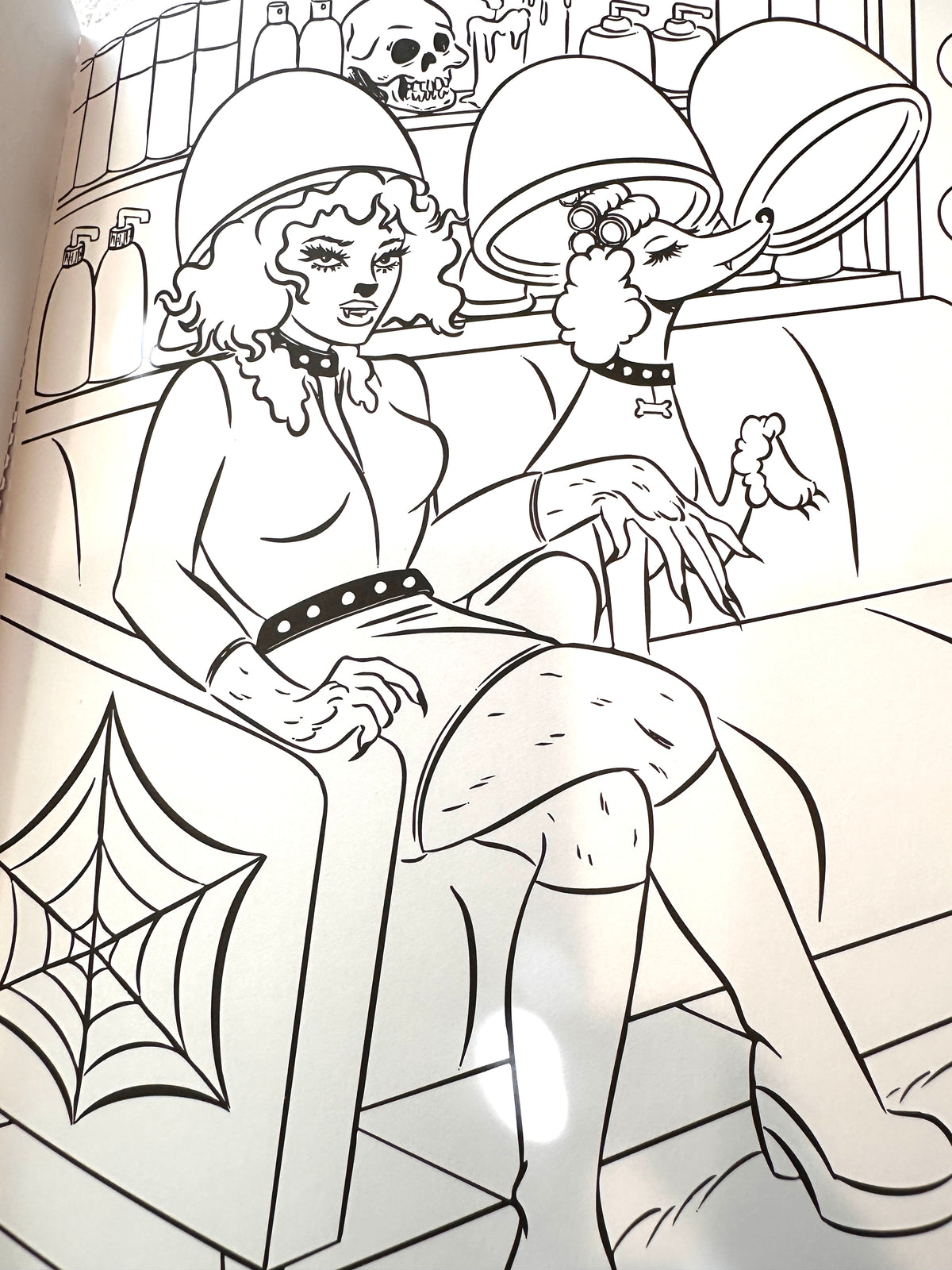 Black and white line art illustration of a woman in a salon setting with a dog, featuring a spiderweb design on the armrest.