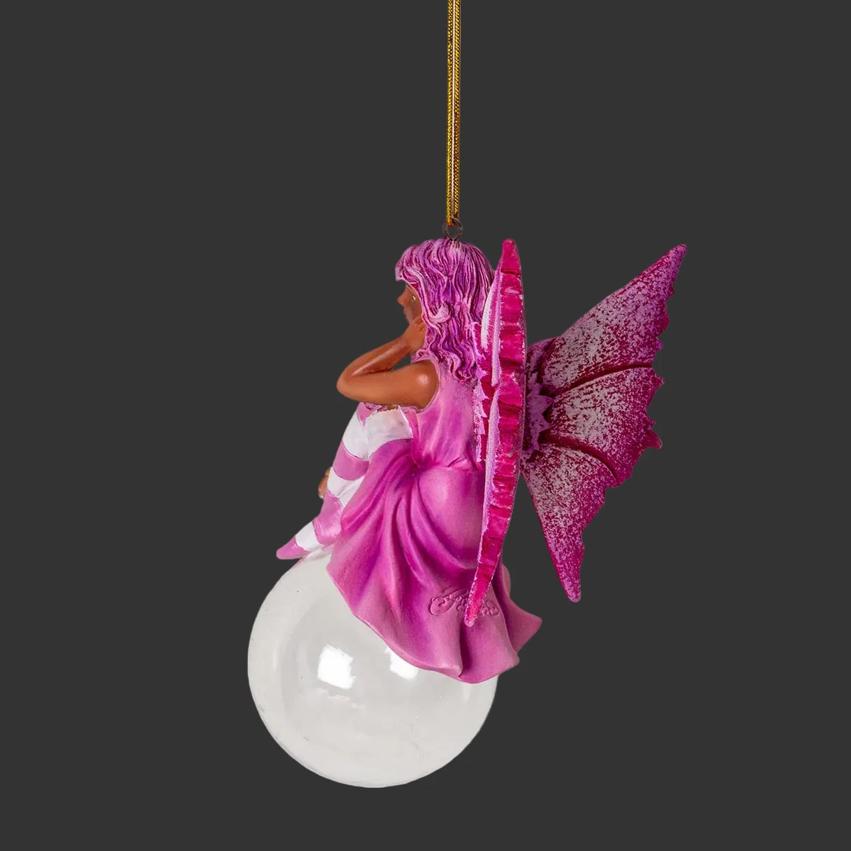 Decorative Amy Brown black fairy ornament with pink wings and dress on sitting on a glass bubble with a black background