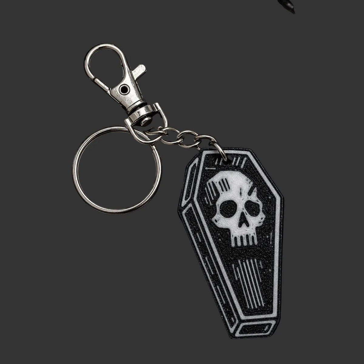 Keychain or bag charm  with skull design on coffin shape on a dark slate surface