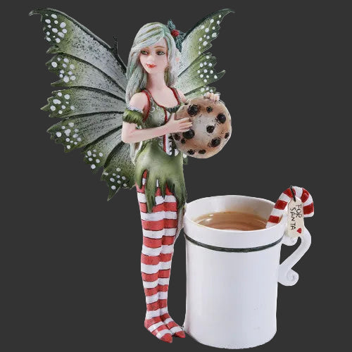 Amy Brown Christmas Fairy figurine with a cookie next to a mug of tea on a black  background