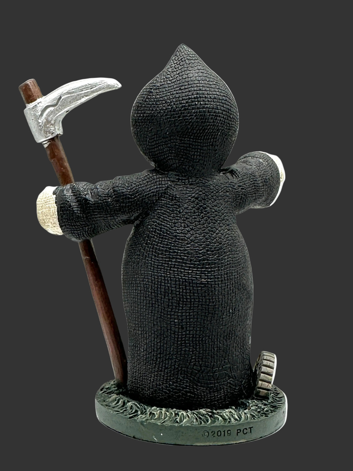 A Grim Reaper Pinhead Monster collectible figurine shown from the back, wearing a textured black robe and holding a scythe with a brown handle and silver blade. The figurine stands on a dark green base against a white background.