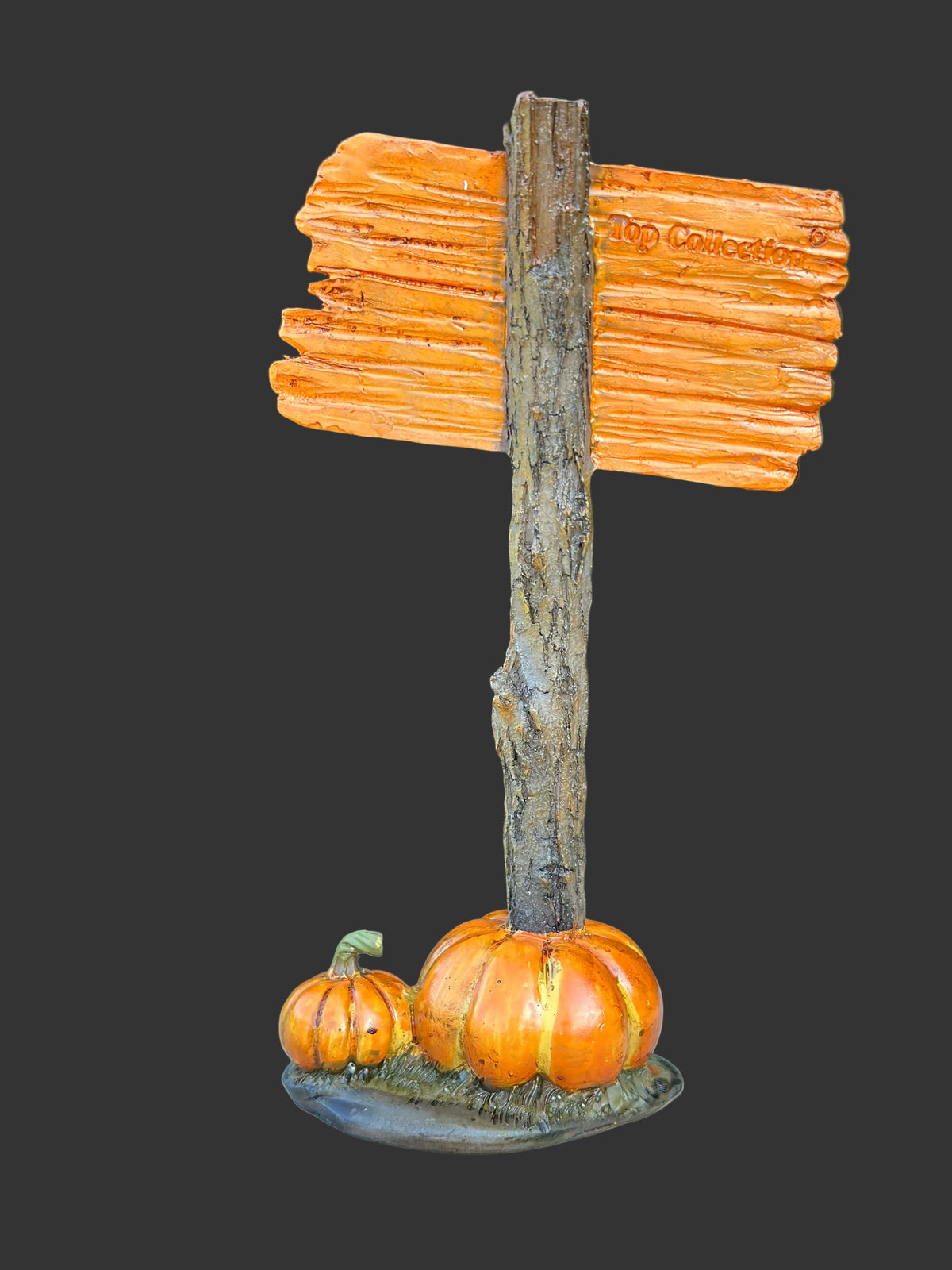 Back view of resin Happy Halloween sign miniature on rustic wooden post with two orange pumpkins at the base, photographed on black background