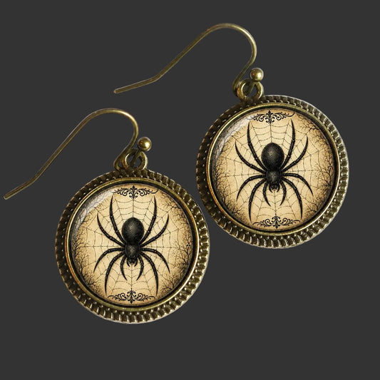 A pair of round drop earrings with antique bronze-toned metal frames and hooks, featuring a black spider on a cracked beige web background.