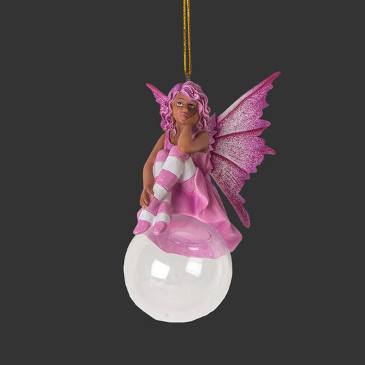 A pink African American fairy Christmas ornament sitting on a clear glass globe, featuring a gold hanging string at the top.