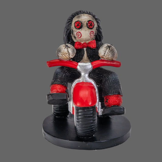 Billy the Puppet Pinhead Monster figurine by Ruben Macias, creepy cute hand-painted resin collectible seated on red tricycle with button eyes and red bow tie, shown on black background