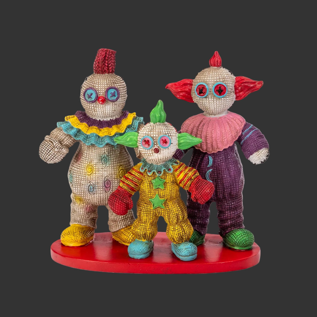 Front view of Killer Klowns from Outer Space Pinhead Monster three-figure set, Bibbo, Shorty, and Slim creepy cute horror collectibles on red display base, black background
