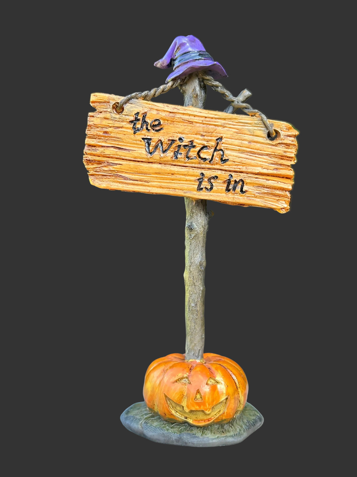 Resin The Witch Is In sign miniature with purple witch hat and glowing jack-o-lantern base on a rustic twig like post