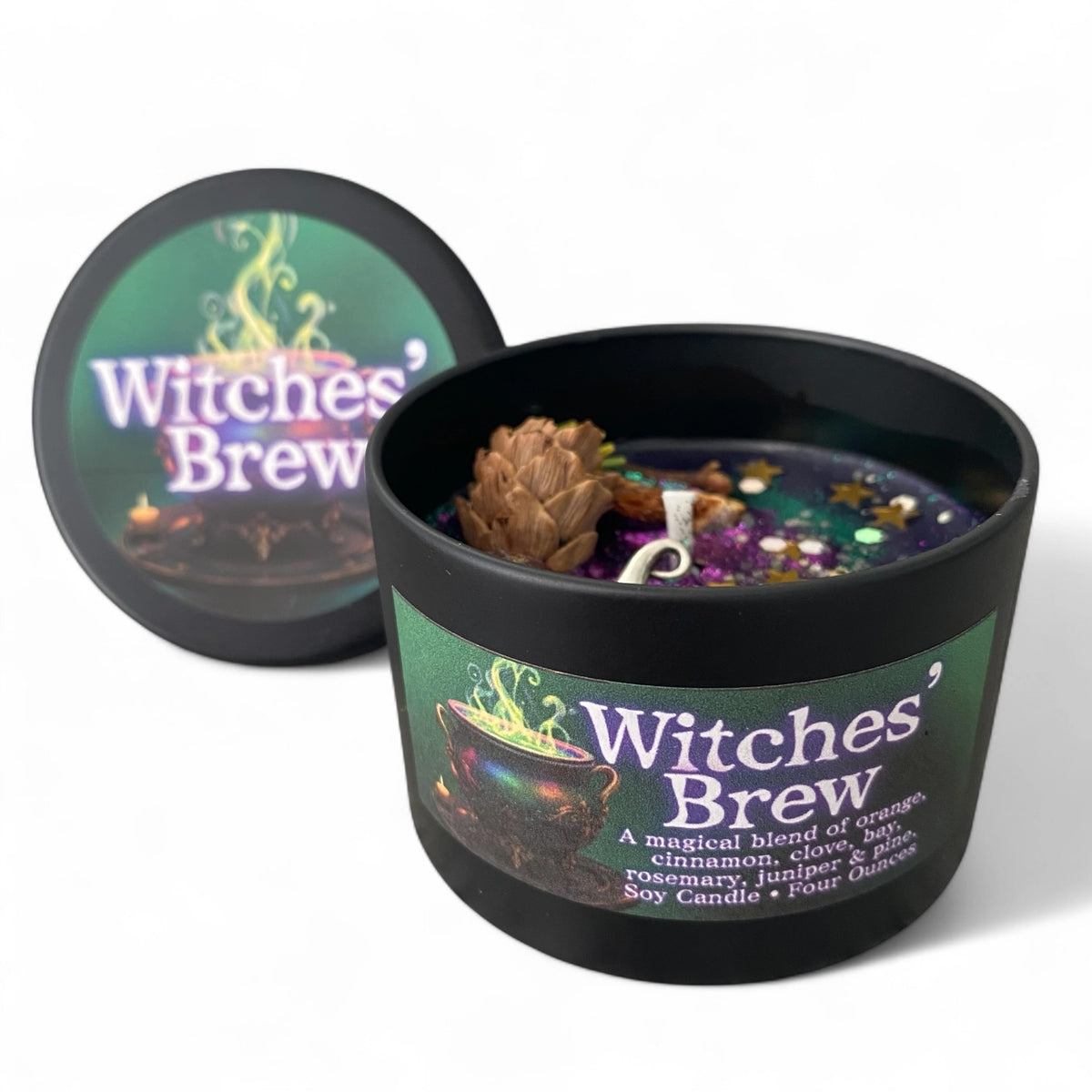 A black soy candle labeled 'Witches' Brew' with a matching lid leaning behind it on a white background. The open candle shows a dark wax surface with a pinecone, small dried botanicals, and a white wick.