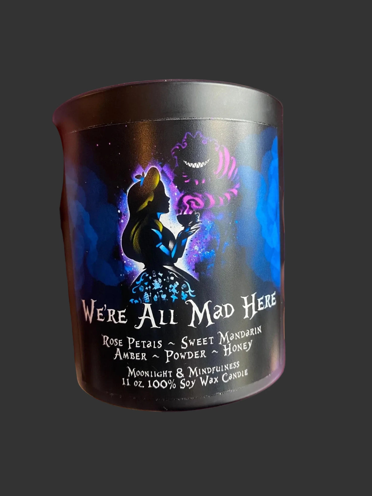 Alice in Wonderland candle with decorative label that reads 
we're all mad here. The label shows Alice and Chesire cat.