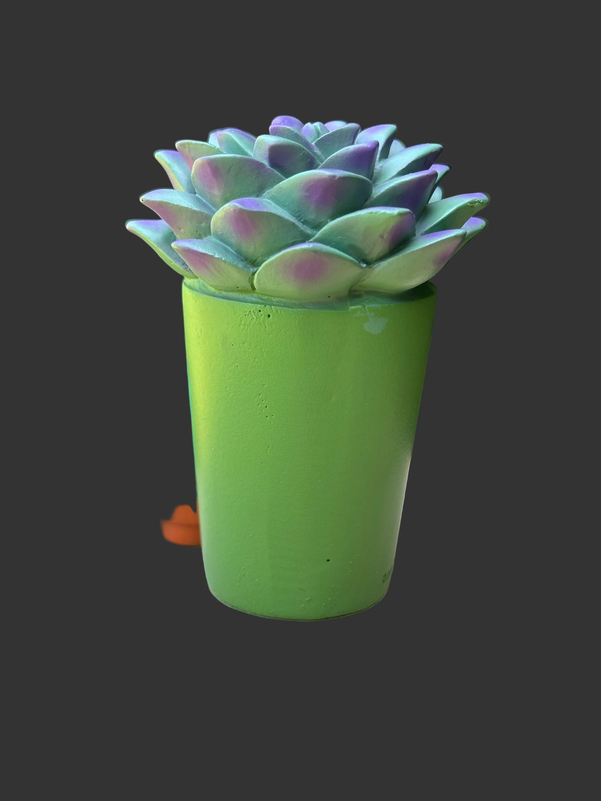 A Furrybones green succulent plant with purple and blue-green variegated leaves, potted in a bright green cylindrical pot. The face is a skull - spooky resin figurine