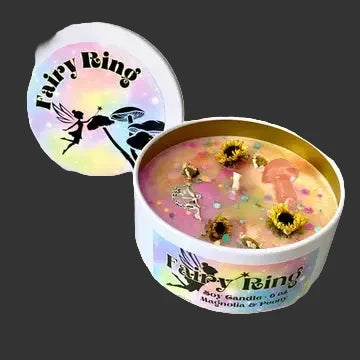 A Fairy Ring scented candle in a white tin with a gold inner rim, shown open with pink wax, glitter, and dried flower petals inside. The matching lid is displayed beside it on a clean white background.
