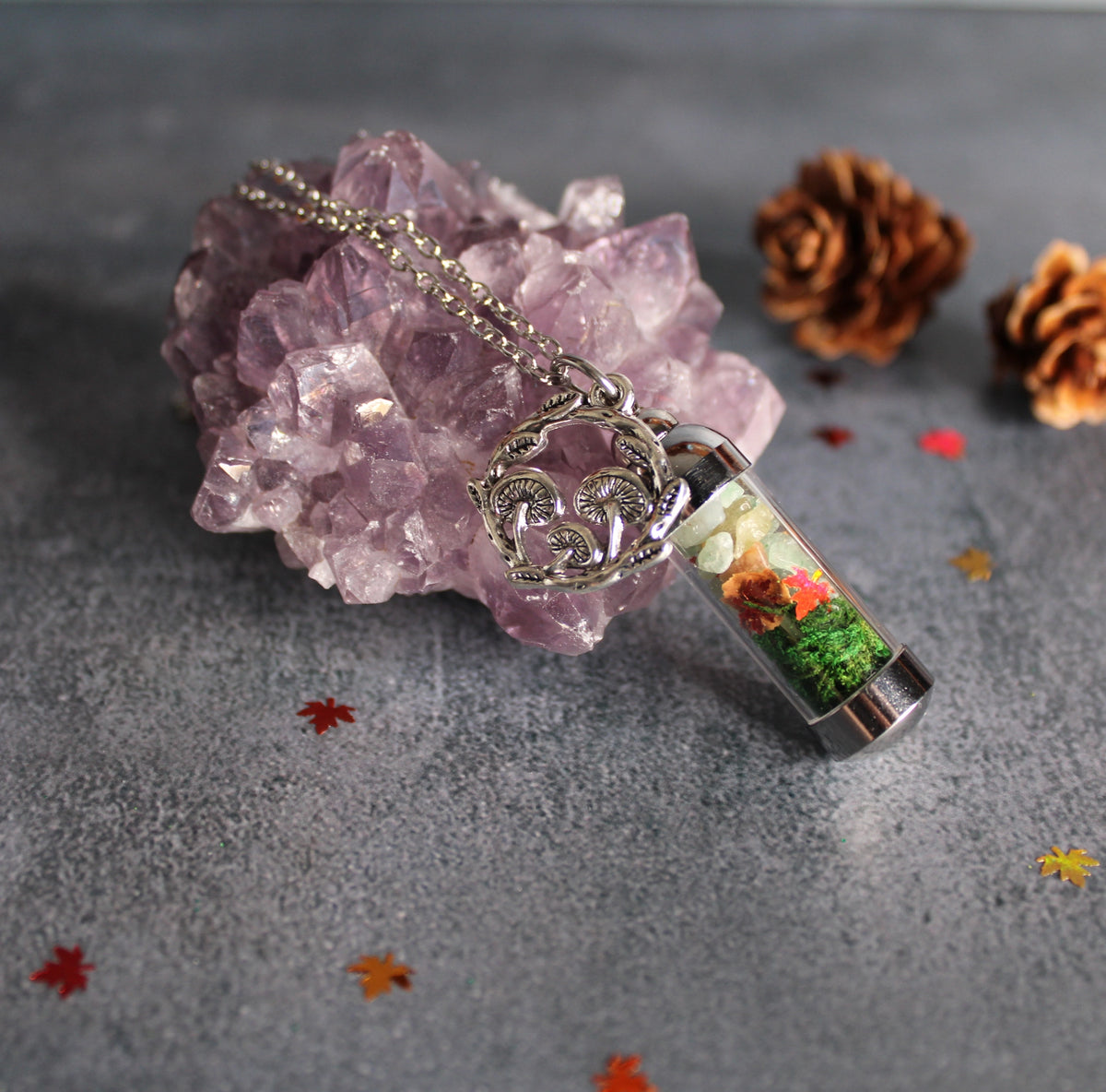 Spell Jar Necklace with a decorative mushroom pendant on a gray surface with crystals and pine cones.