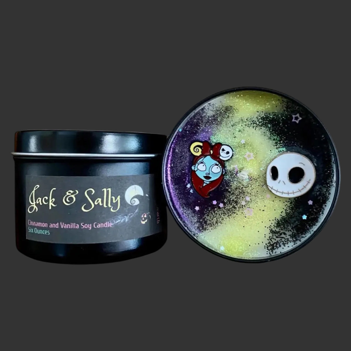 A black metal candle tin labeled 'Jack & Sally' with the lid placed beside it. The lid features a colorful galaxy-style design with purple, yellow-green, and black speckling, plus cartoon character faces.