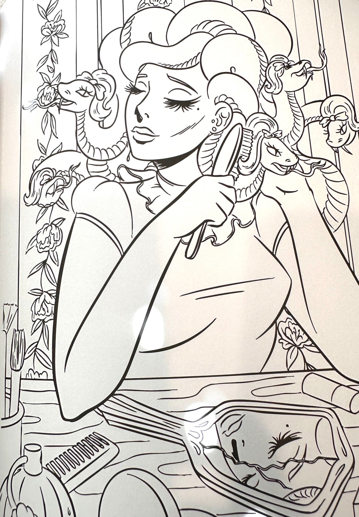 Black and white line art illustration of a woman with snakes around her head, holding a brush near her face, with a mirror and styling tools in the foreground.