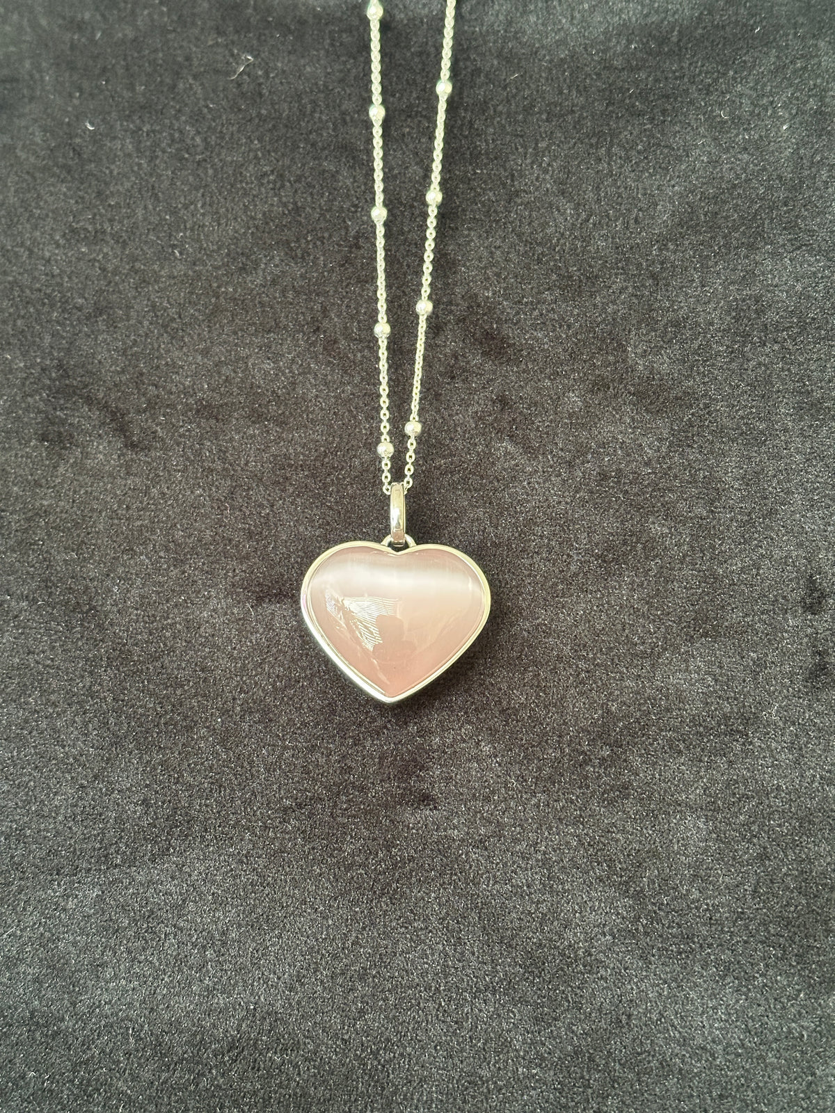 Pink cat eye heart necklace with beaded stainless steel chain on a dark background