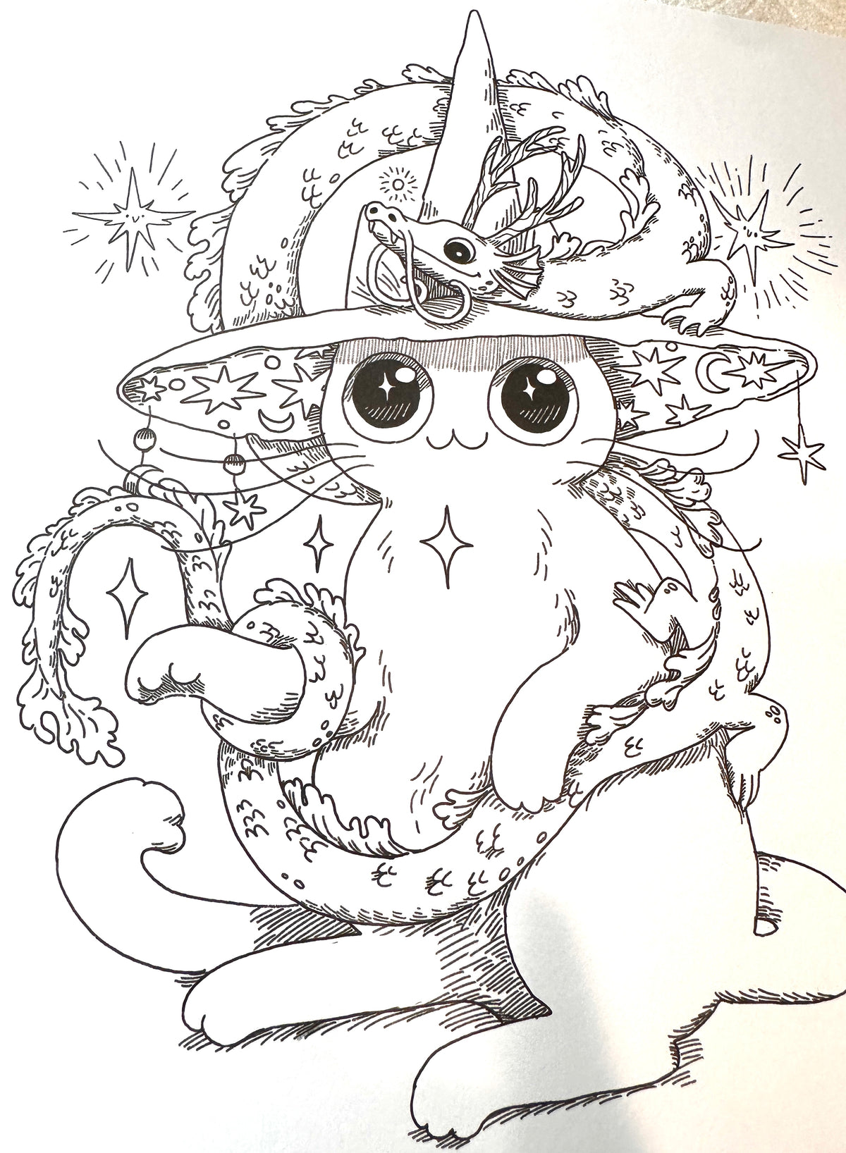 Black and white line art illustration of a cute, fluffy cat wearing a wizard hat with stars, moons, and a unicorn horn, holding a wand.