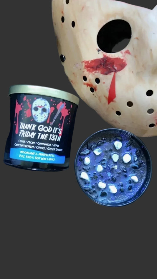 Candle with 'Thank God it's Friday the 13th' text, grinder, and mask on a dark background