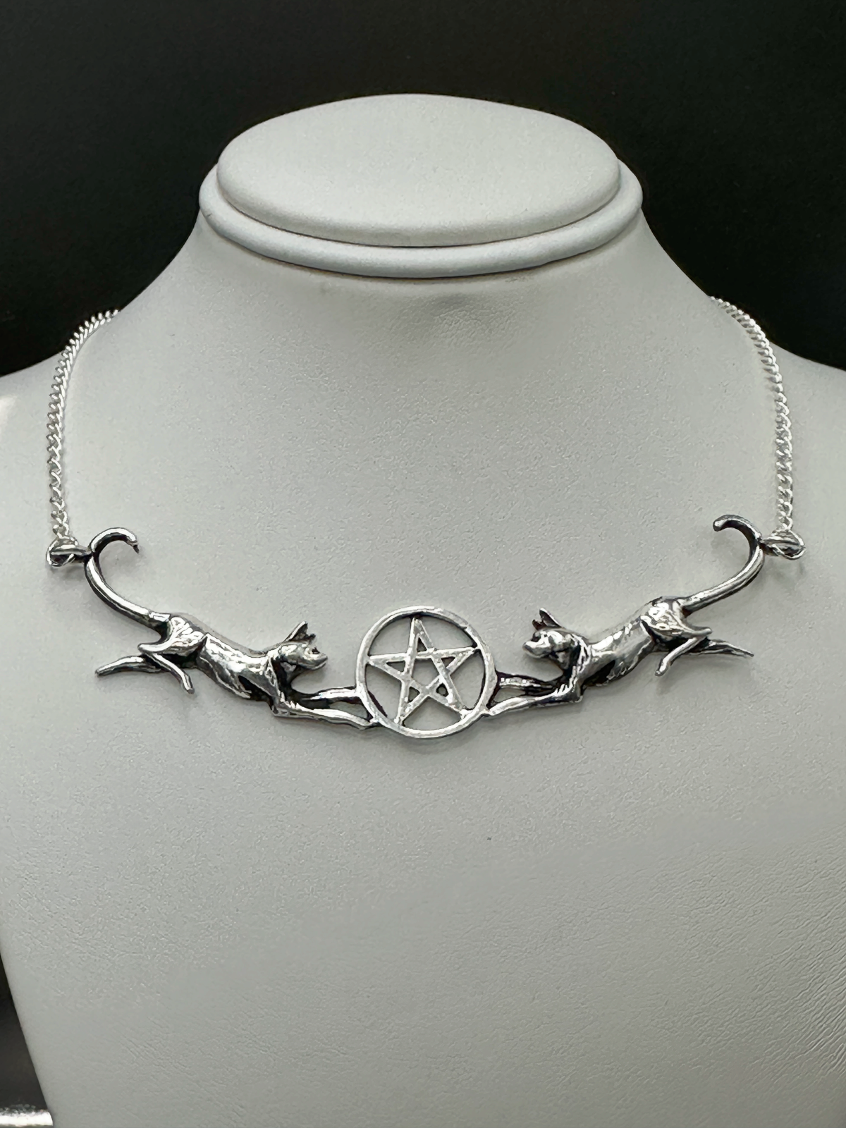 Twin Cat Pentacle necklace in silver pewter with two mirrored cats flanking a pentacle centerpiece displayed on a jewelry bust