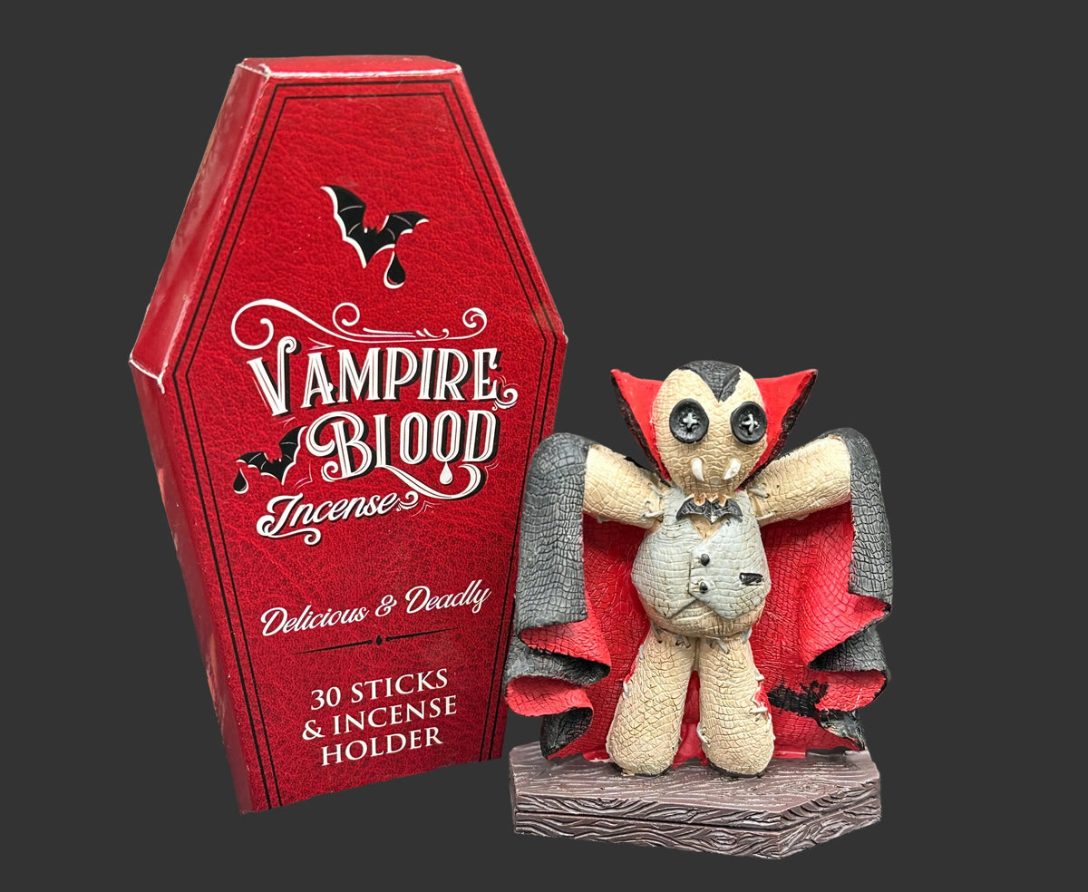 Vampire Blood Incense product display featuring a red coffin-shaped box and a small stitched vampire figure with a red cape, set against a gothic graveyard backdrop.