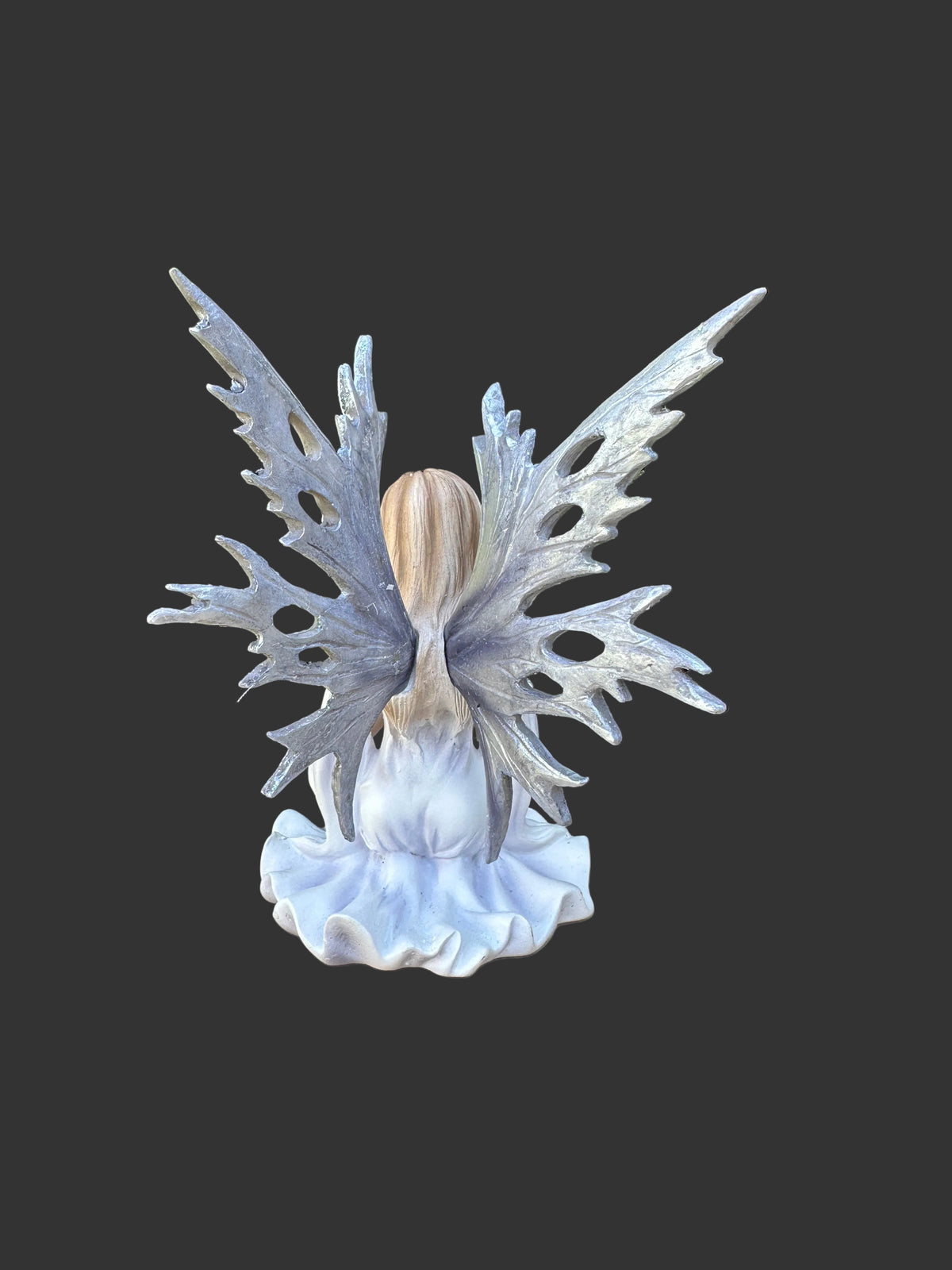A fantasy Dream Eden winter fairy figurine with large, intricate silver-blue wings, a light wood-textured head, and a white ruffled base, shown against a solid dark gray background.